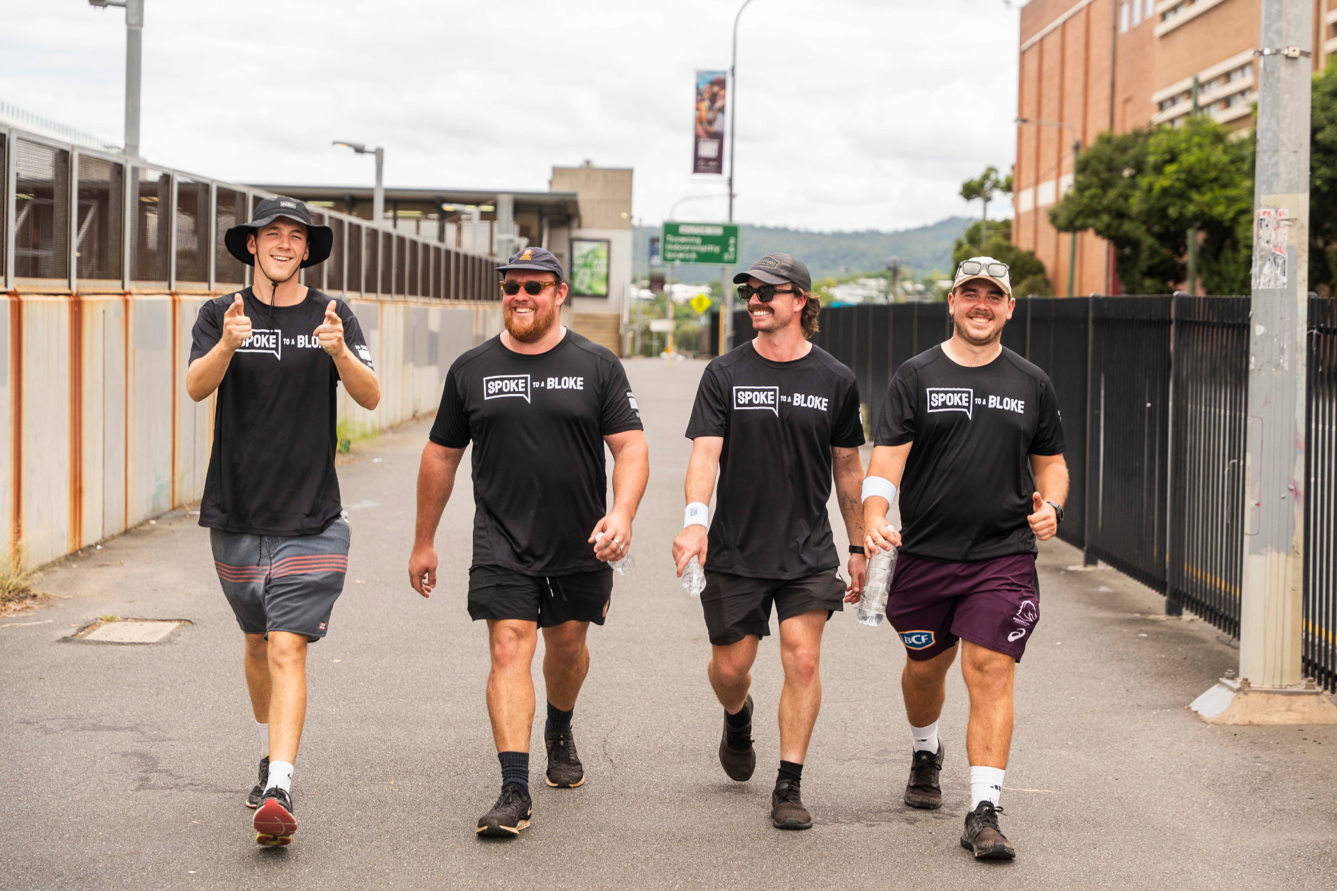 Four young men in Spoke to a Bloke shirts walking together and smiling